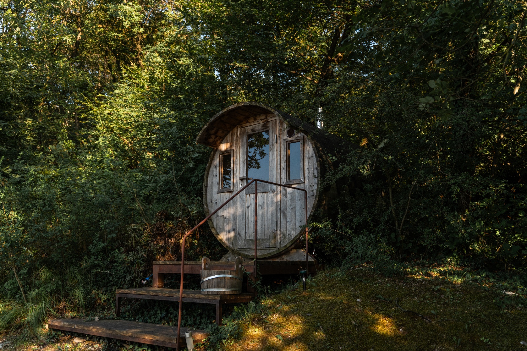 Wood-fired barrel sauna tucked into the trees by the pool