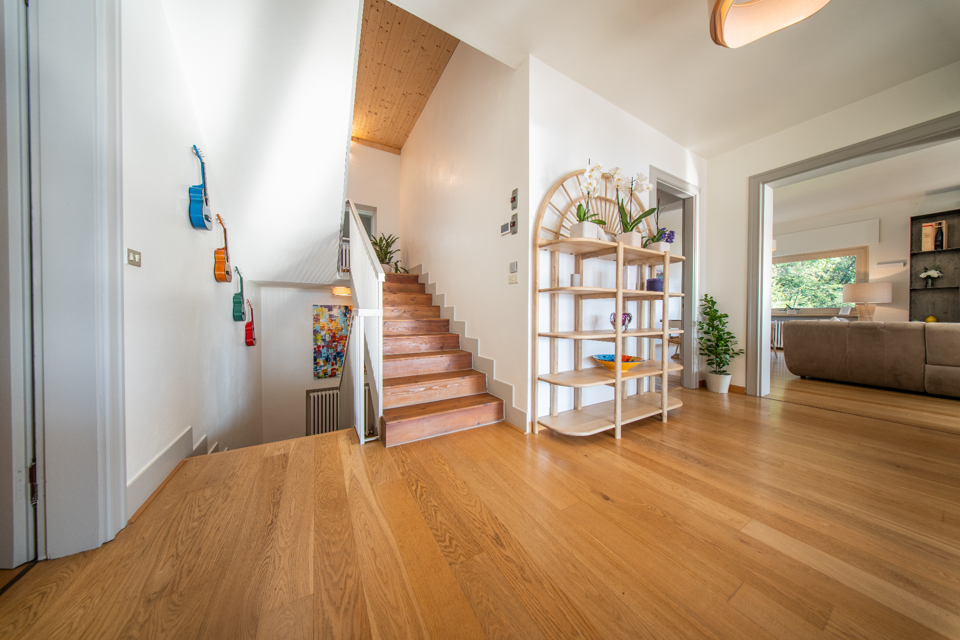 Entrance hall with wooden staircase, guitars on the wall and open living room