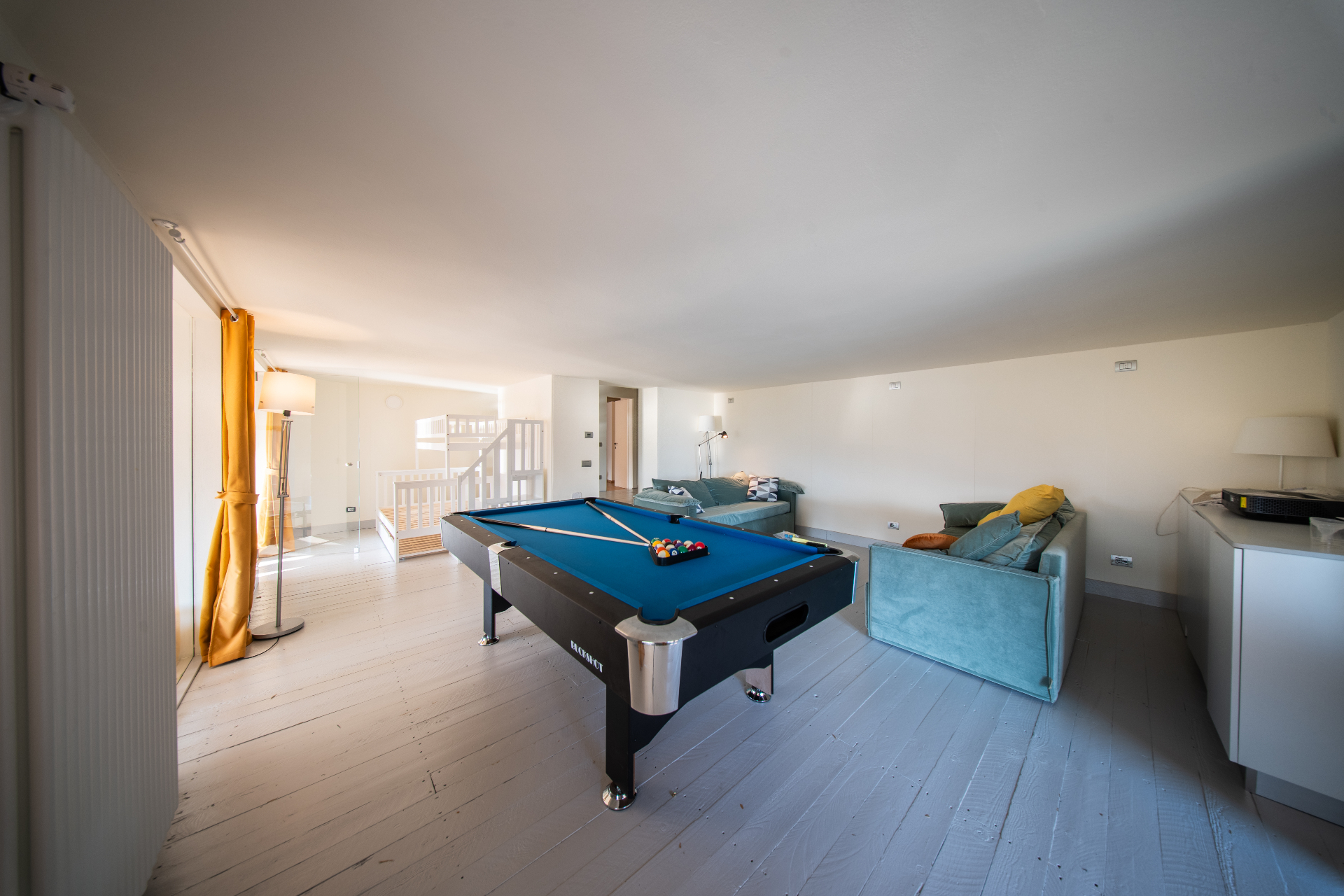 Games room with blue-felt pool table, lounge sofas and bunk beds