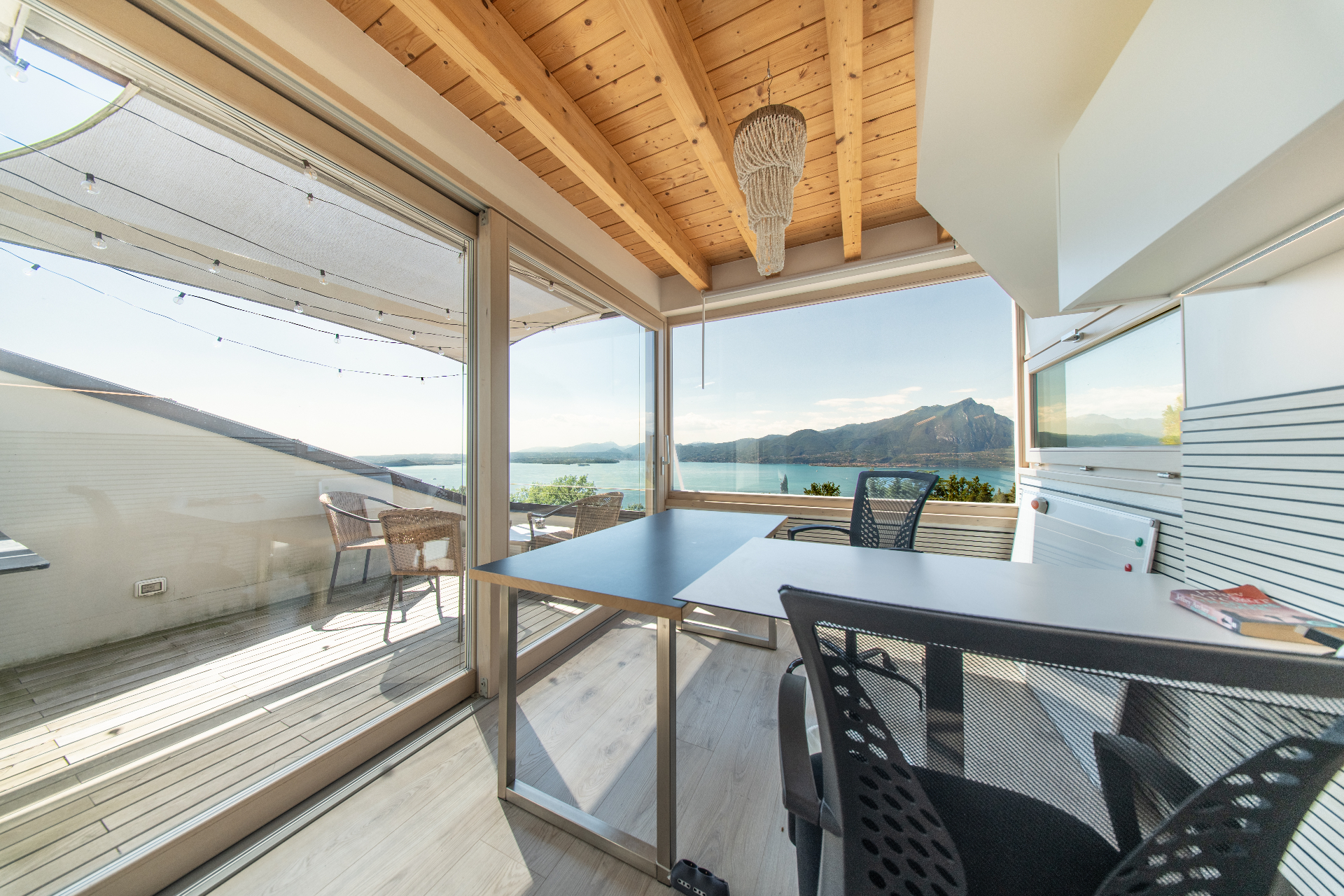 Home office desk framed by floor-to-ceiling windows over Lake Garda