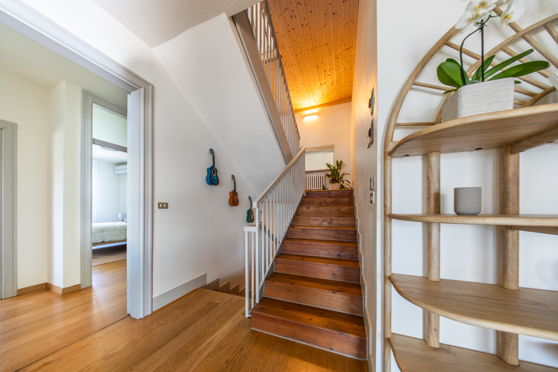 Staircase with pitched wooden ceiling and orchid-topped shelving