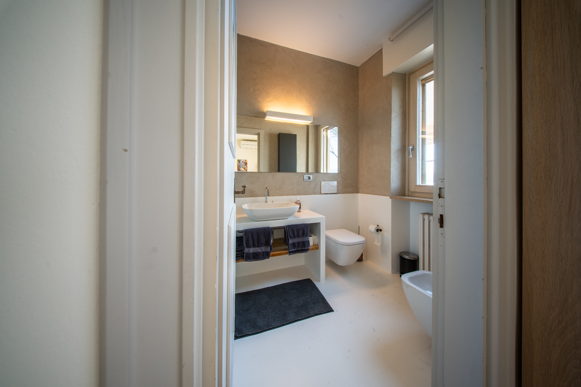 Minimalist bathroom in warm plaster and travertine