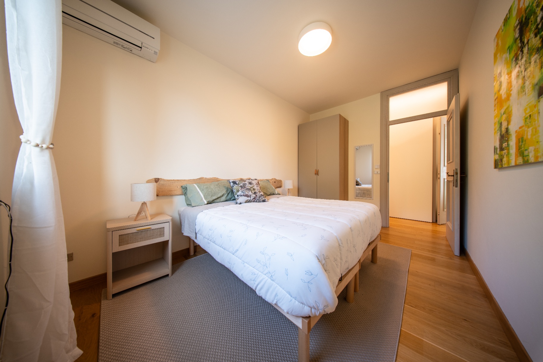Double bedroom with green pillows and abstract artwork