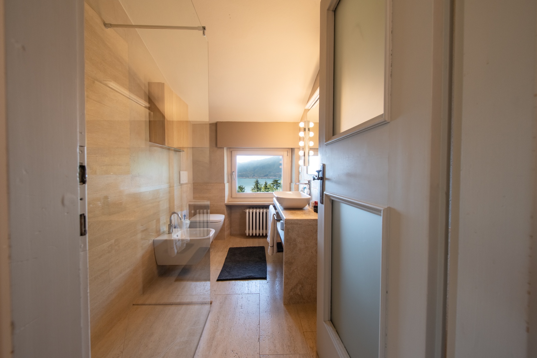 Travertine ensuite bathroom with a Lake Garda window